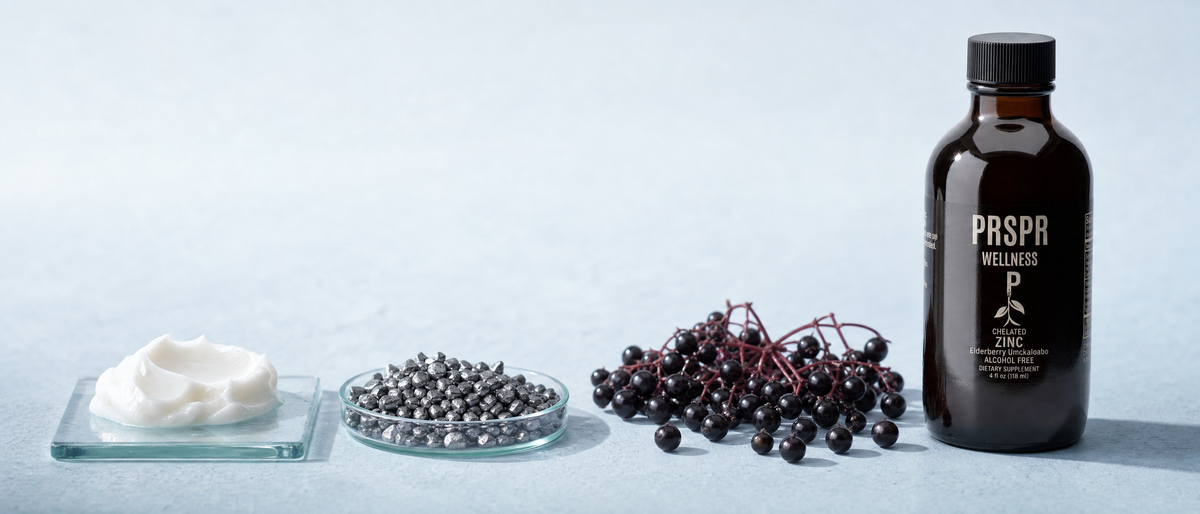 PRSPR Wellness Chelated Zinc plus Elderberry bottle on pale blue beside white mineral cream, grey metallic pellets and elderberries