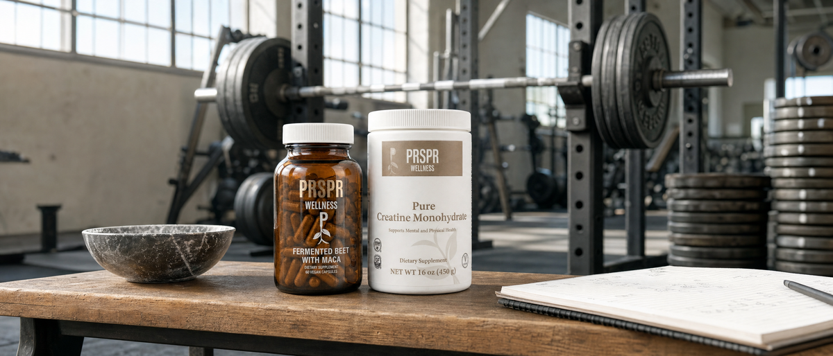 PRSPR Fermented Beet With Maca jar and Pure Creatine Monohydrate tub from Nature's BBL DELUXE on a gym bench in front of a loaded barbell