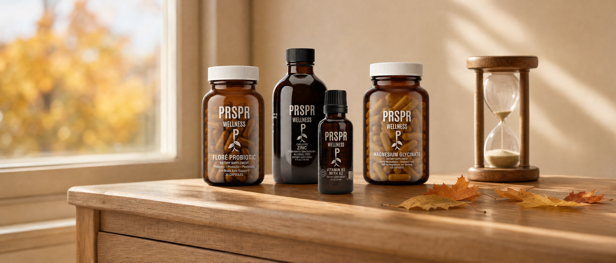 PRSPR Wellness FLORÉ Probiotic, Chelated Zinc, Vitamin D3 with K2 and Magnesium Glycinate bottles on an oak side table beside an hourglass and fallen autumn maple leaves in late-afternoon light.