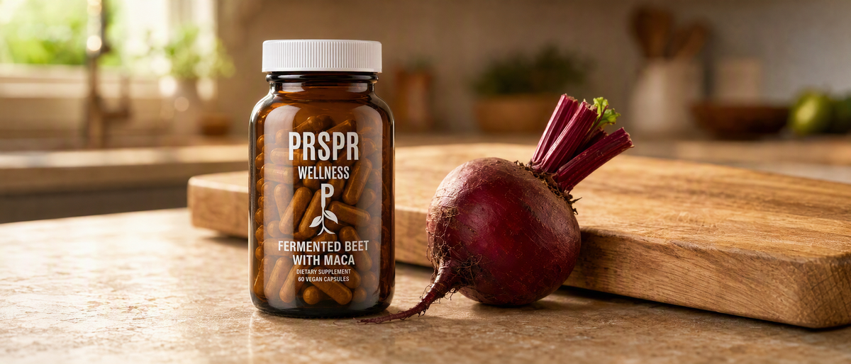 PRSPR Wellness Fermented Beet with Maca capsule bottle on a kitchen counter beside a fresh whole beet and wooden cutting board
