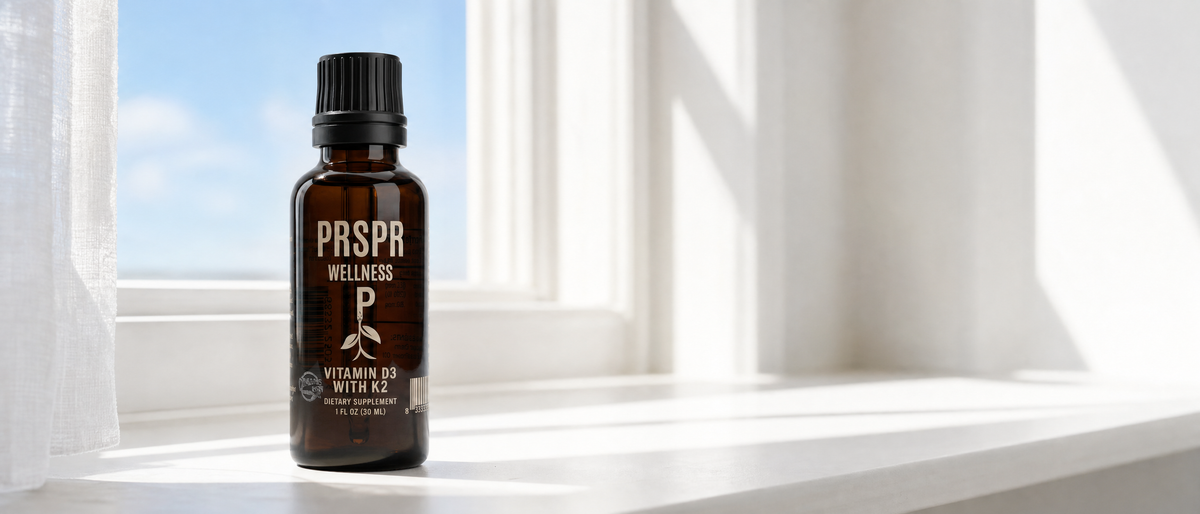PRSPR Wellness Vitamin D3 plus K2 MK7 liquid supplement bottle on a bright sunlit windowsill