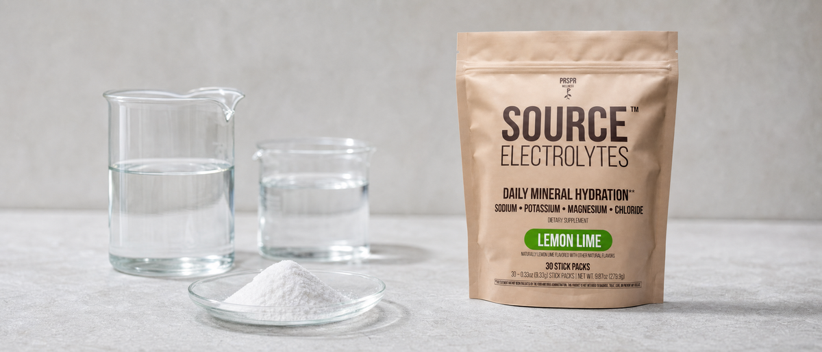 PRSPR Wellness Source Electrolytes stick packs beside laboratory beakers and a small spill of fine white crystalline powder