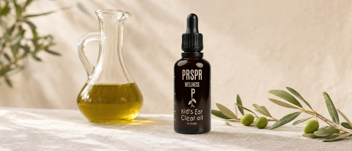 PRSPR Wellness Kids Ear Clear Oil dropper bottle beside a glass cruet of olive oil and an olive branch