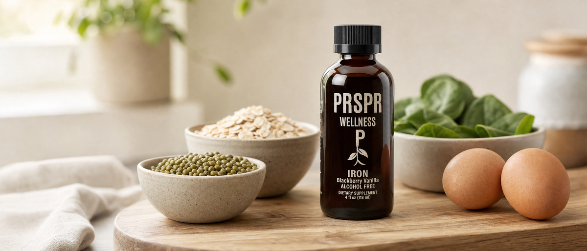 PRSPR Wellness Liquid Iron bottle beside bowls of oats, green legumes and spinach and two brown eggs
