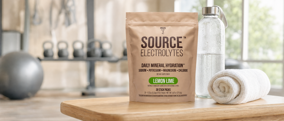 Source Electrolytes Lemon Lime pouch on a wooden gym bench beside a rolled white towel and a glass water bottle beaded with droplets