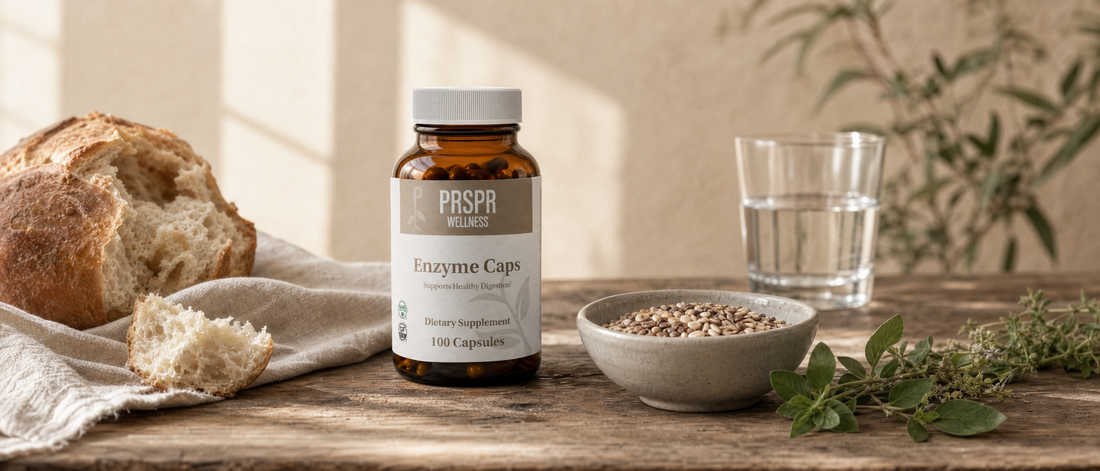 PRSPR Wellness Enzyme Caps on a farmhouse table beside sourdough bread, a bowl of whole grains, fresh herbs and a glass of water