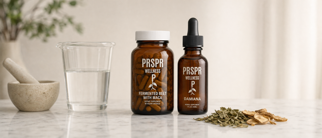 The PRSPR Wellness Love Bundle capsule jar and Damiana dropper bottle on white marble beside a glass beaker of water, a mortar and pestle, dried damiana leaves and maca slices