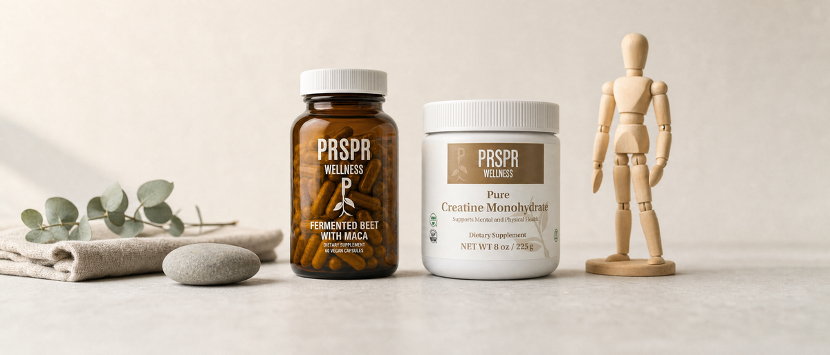 The PRSPR Wellness Natures BBL bundle on pale concrete beside a wooden artist's posing mannequin, a grey river stone and a sprig of eucalyptus