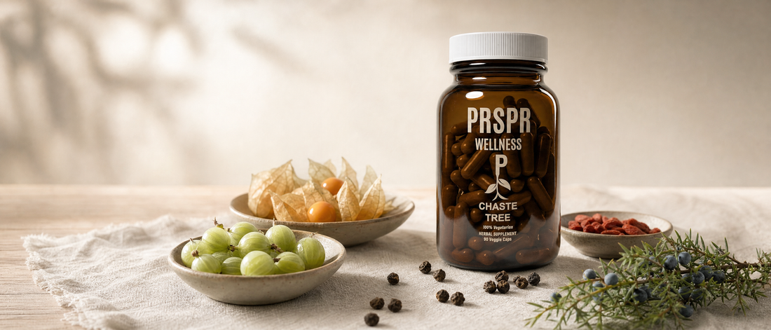 Chaste Tree amber capsule jar on a linen-covered table beside small dishes of green gooseberries, golden berries in papery husks and dried goji berries, a juniper sprig with blue berries, and small dark dried fruits scattered on the linen